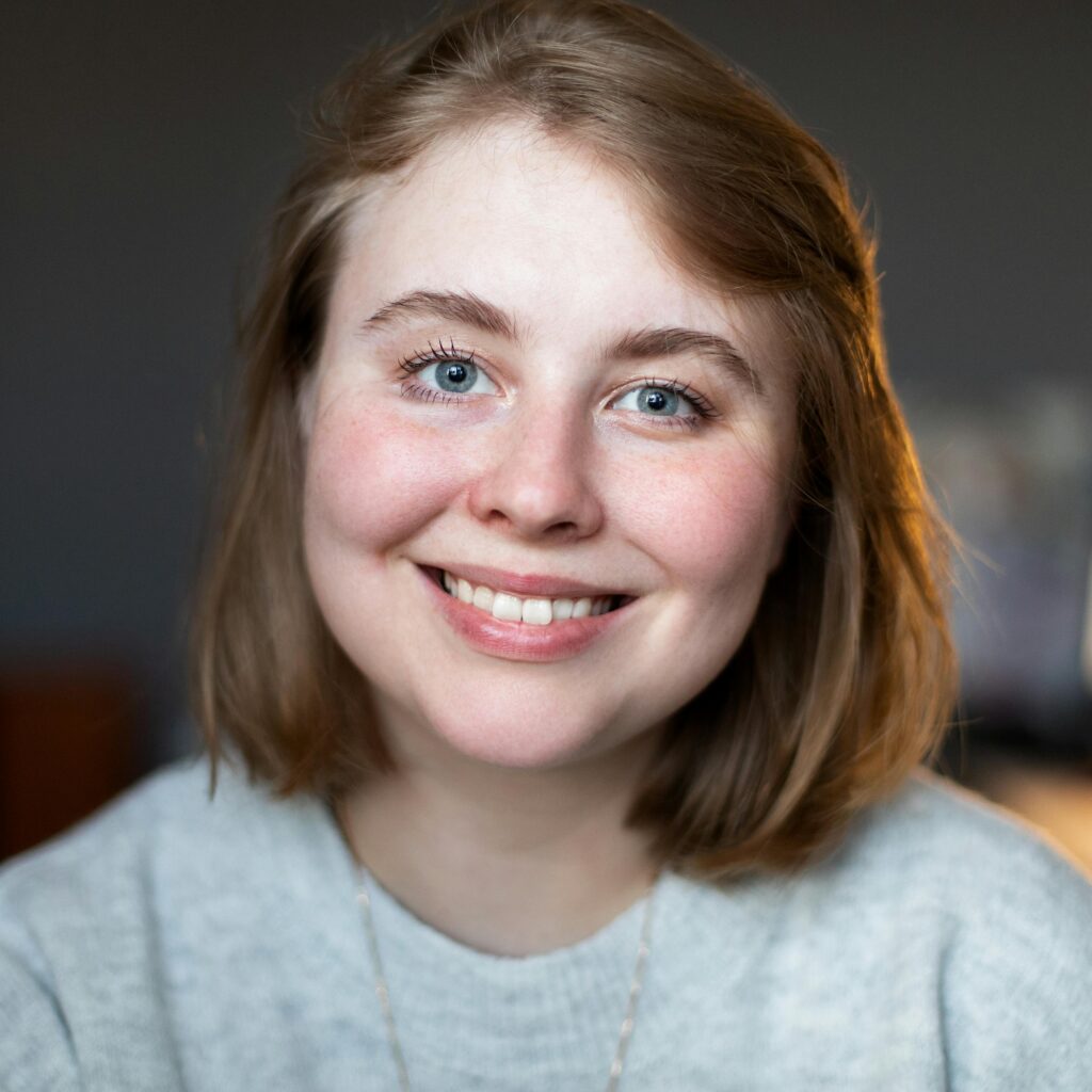 A cheerful woman with short blonde hair smiling indoors, showcasing natural beauty.